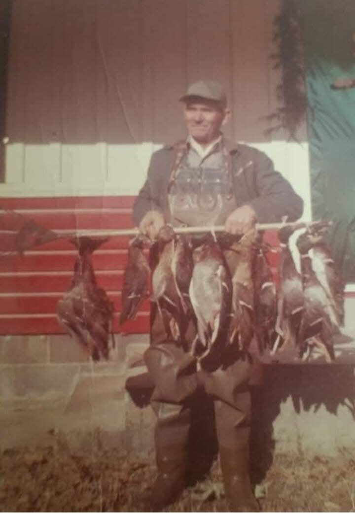 A hunter with a heavy strap of ducks in front of the camp — a Dirty Duck Outfitters heritage photo