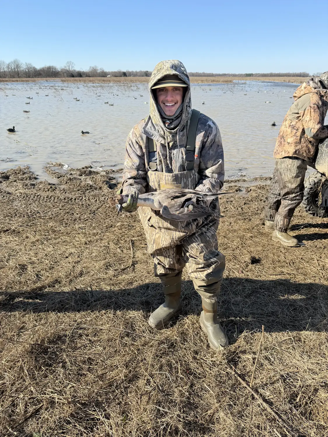 Hunter geared up on the levee with waders and a strap of mallards