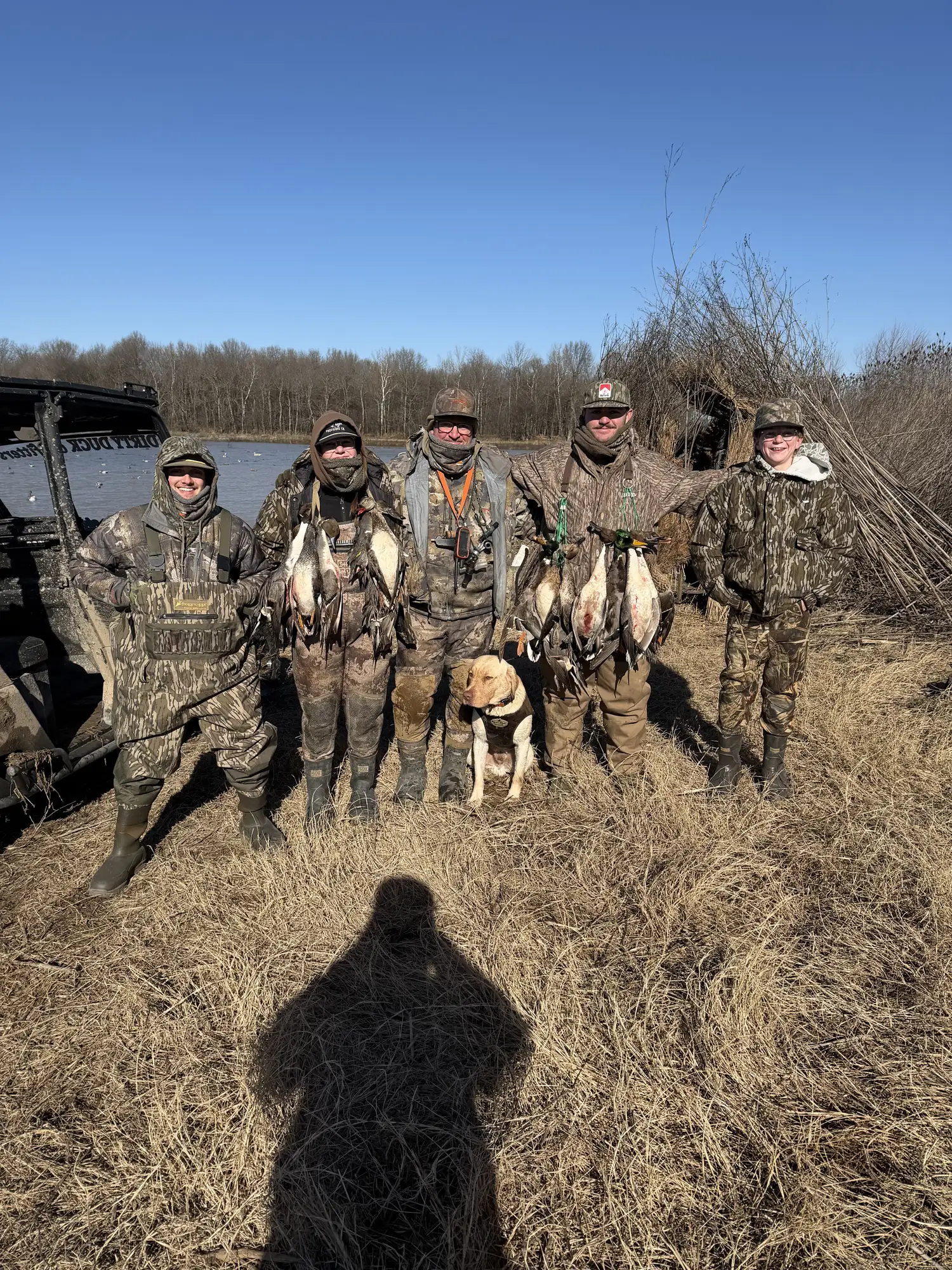 Hunting party in a brushed field blind with birds laid out